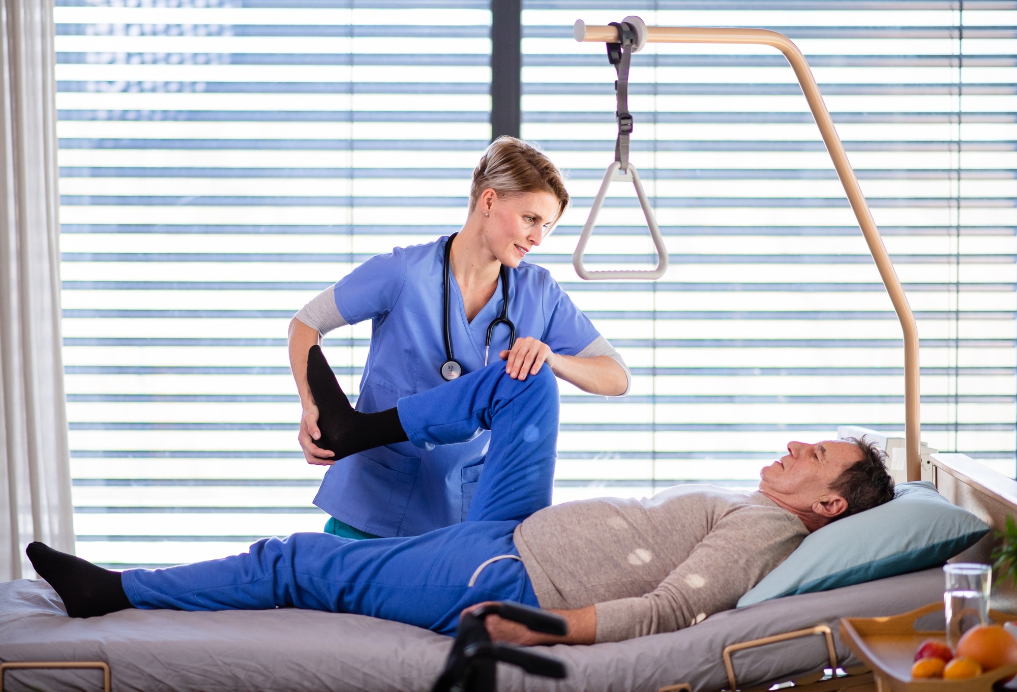 A healthcare worker and senior patient in hospital, physiotherapy.